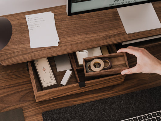 Hand reaching for a wooden desk organizer on a wooden desk with office supplies. | walnut,