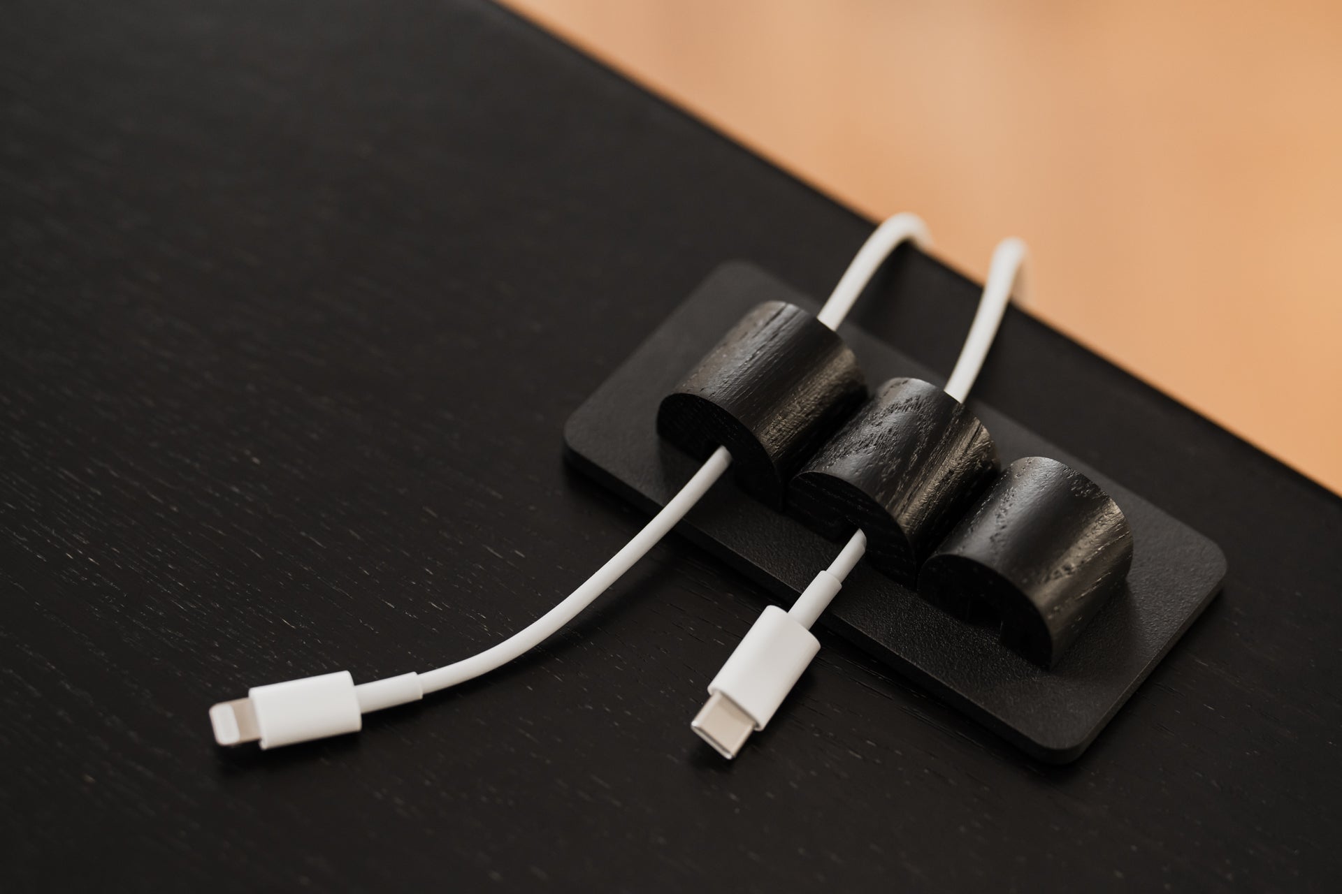 White USB-C cables on a black surface with a brown background | black, 