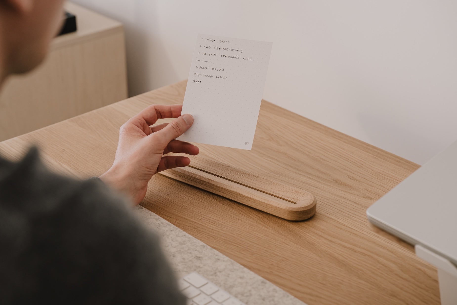 Person holding a paper to-do list at a wooden desk | oak