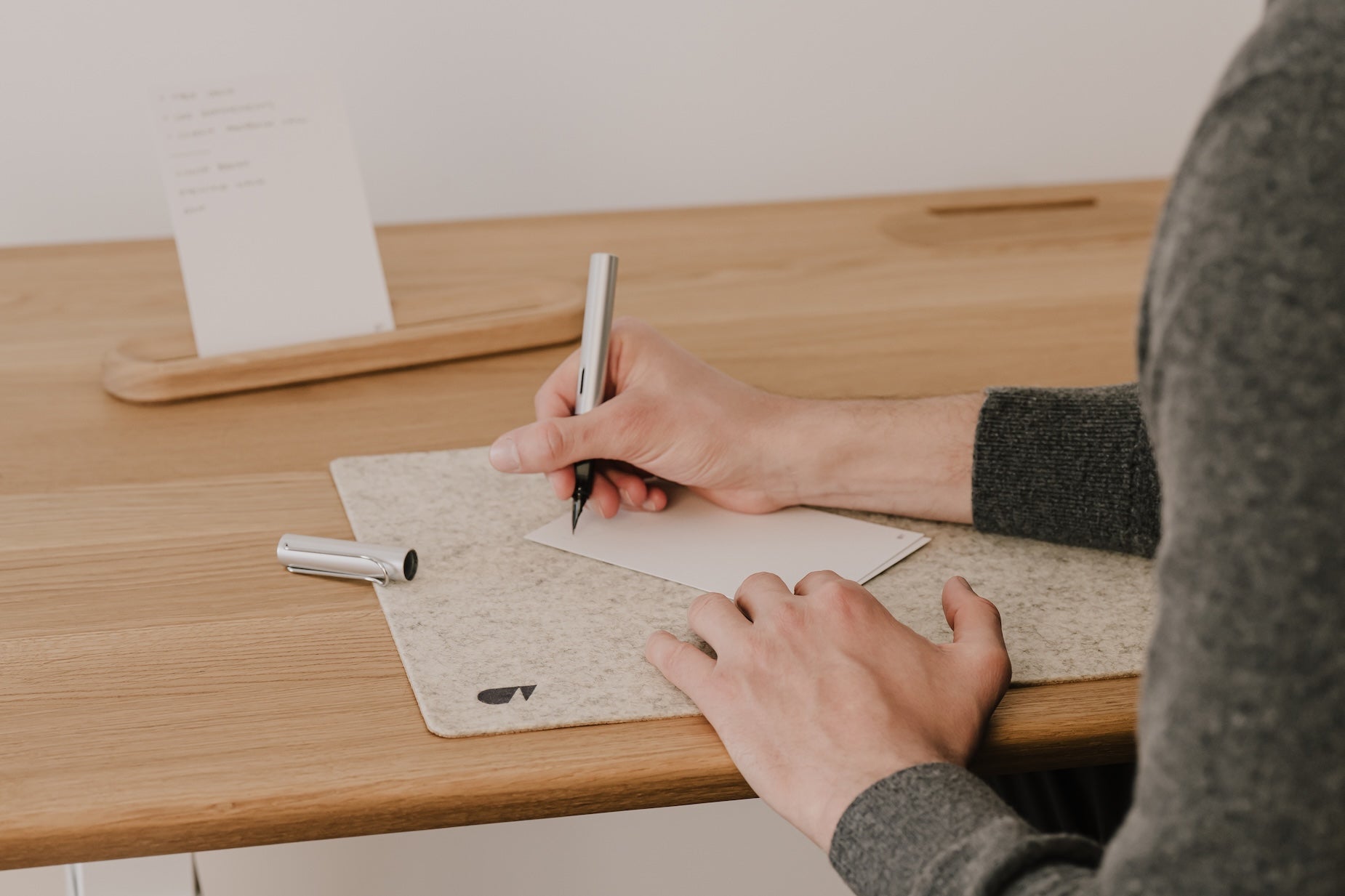 Person writing a to-do list with a pen at a wooden desk | oak