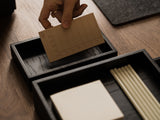 Person placing a brown card into a black Oakywood Valet Tray – stylish black tray for office | black, 